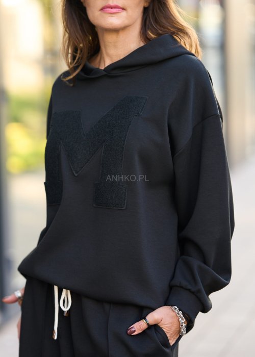 Czarny komplet dresowy damski z oversize’ową bluzą z literą M i szerokimi spodniami z elastycznym pasem, stylizacja w minimalistycznym, miejskim klimacie.