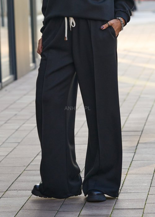 Czarny komplet dresowy damski z oversize’ową bluzą z literą M i szerokimi spodniami z elastycznym pasem, stylizacja w minimalistycznym, miejskim klimacie.