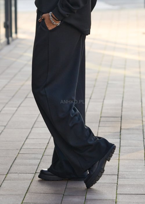 Czarny komplet dresowy damski z oversize’ową bluzą z literą M i szerokimi spodniami z elastycznym pasem, stylizacja w minimalistycznym, miejskim klimacie.