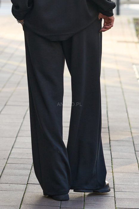 Czarny komplet dresowy damski z oversize’ową bluzą z literą M i szerokimi spodniami z elastycznym pasem, stylizacja w minimalistycznym, miejskim klimacie.