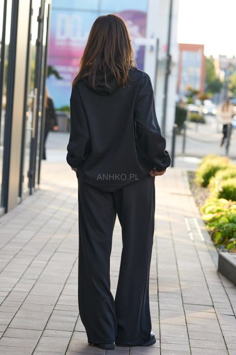 Czarny komplet dresowy damski z oversize’ową bluzą z literą M i szerokimi spodniami z elastycznym pasem, stylizacja w minimalistycznym, miejskim klimacie.