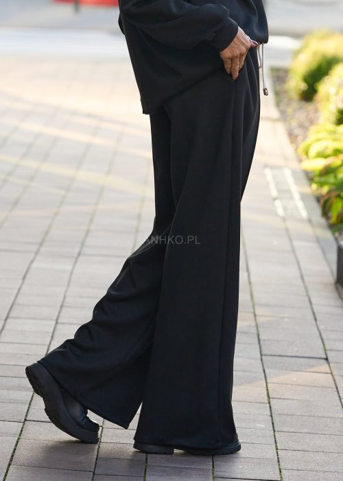 Czarny komplet dresowy damski z oversize’ową bluzą z literą M i szerokimi spodniami z elastycznym pasem, stylizacja w minimalistycznym, miejskim klimacie.