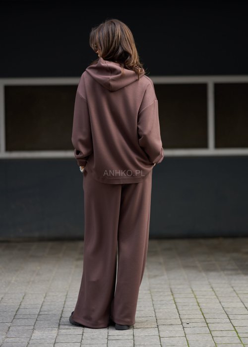 Brązowy komplet dresowy damski z oversize’ową bluzą z literą M i szerokimi spodniami z elastycznym pasem, stylizacja w nowoczesnym miejskim klimacie