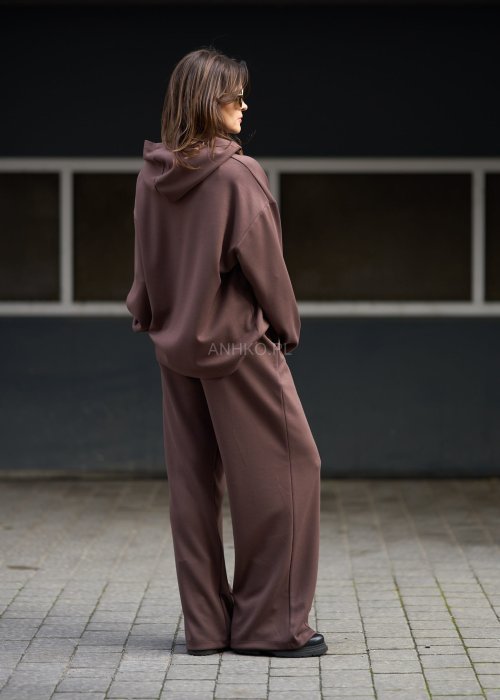 Brązowy komplet dresowy damski z oversize’ową bluzą z literą M i szerokimi spodniami z elastycznym pasem, stylizacja w nowoczesnym miejskim klimacie