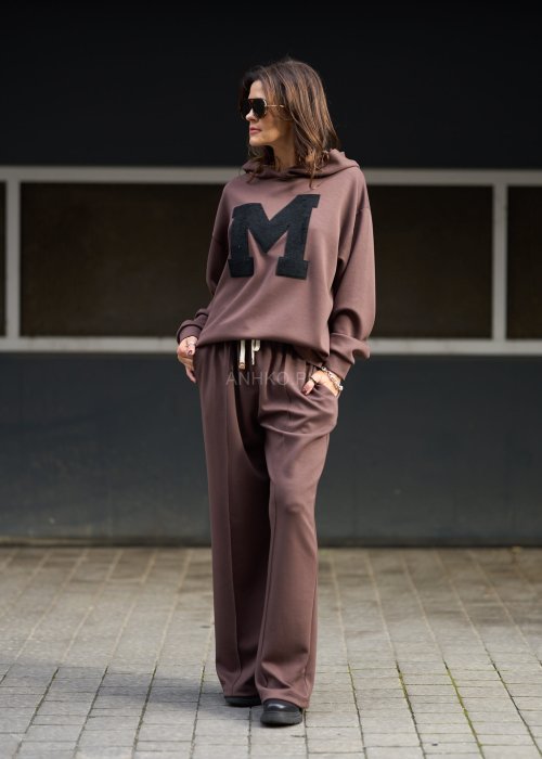 Brązowy komplet dresowy damski z oversize’ową bluzą z literą M i szerokimi spodniami z elastycznym pasem, stylizacja w nowoczesnym miejskim klimacie