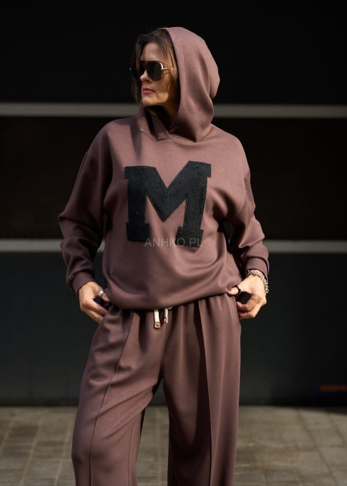 Brązowy komplet dresowy damski z oversize’ową bluzą z literą M i szerokimi spodniami z elastycznym pasem, stylizacja w nowoczesnym miejskim klimacie