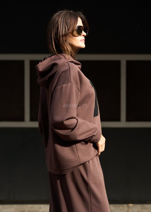 Brązowy komplet dresowy damski z oversize’ową bluzą z literą M i szerokimi spodniami z elastycznym pasem, stylizacja w nowoczesnym miejskim klimacie