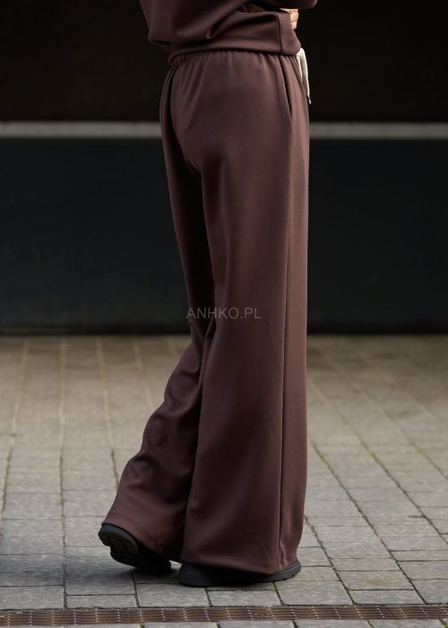 Brązowy komplet dresowy damski z oversize’ową bluzą z literą M i szerokimi spodniami z elastycznym pasem, stylizacja w nowoczesnym miejskim klimacie