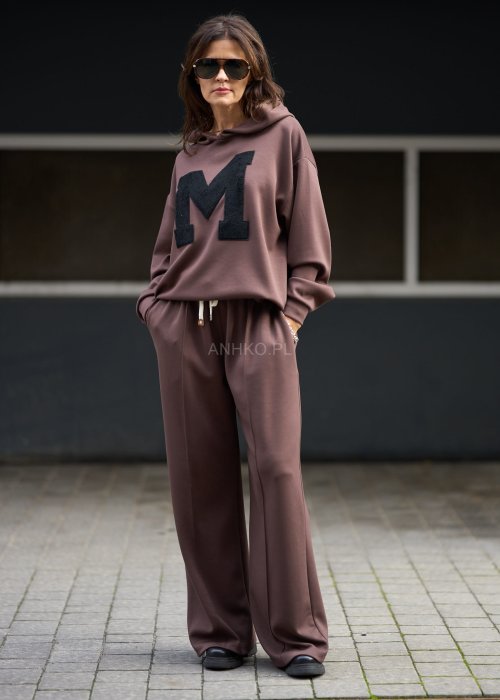 Brązowy komplet dresowy damski z oversize’ową bluzą z literą M i szerokimi spodniami z elastycznym pasem, stylizacja w nowoczesnym miejskim klimacie