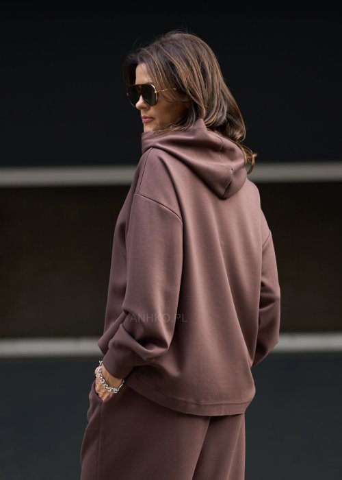 Brązowy komplet dresowy damski z oversize’ową bluzą z literą M i szerokimi spodniami z elastycznym pasem, stylizacja w nowoczesnym miejskim klimacie