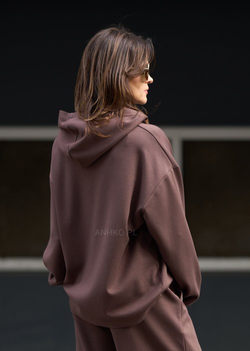 Brązowy komplet dresowy damski z oversize’ową bluzą z literą M i szerokimi spodniami z elastycznym pasem, stylizacja w nowoczesnym miejskim klimacie