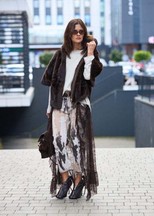 Stylowa damska kamizelka z ciemnobrązowego sztucznego futra z kapturem. Elegancka i ciepła, idealna jako warstwa wierzchnia na chłodniejsze dni.