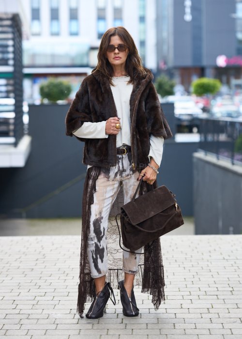 Stylowa damska kamizelka z ciemnobrązowego sztucznego futra z kapturem. Elegancka i ciepła, idealna jako warstwa wierzchnia na chłodniejsze dni.