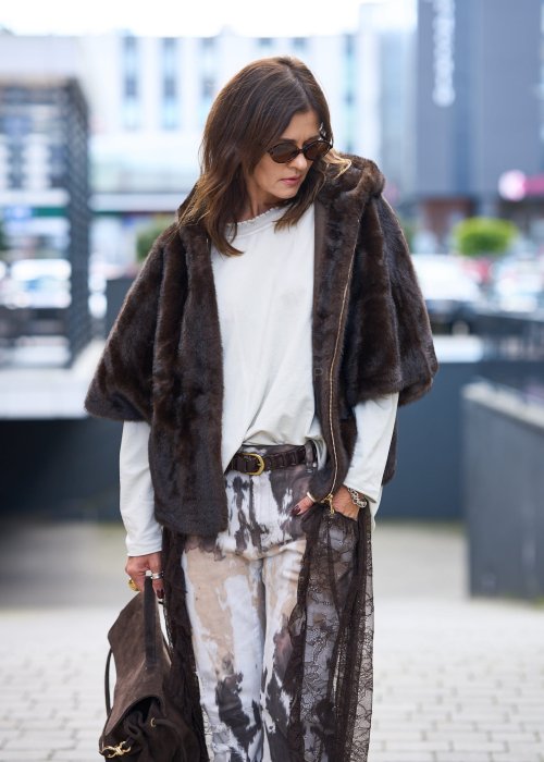 Stylowa damska kamizelka z ciemnobrązowego sztucznego futra z kapturem. Elegancka i ciepła, idealna jako warstwa wierzchnia na chłodniejsze dni.