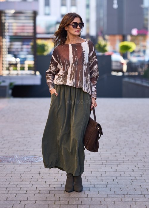 Spódnica maxi w kolorze khaki z elastyczną talią i kieszeniami, o luźnym kroju, zestawiona z wzorzystą bluzką i botkami na słupku w miejskiej stylizacji.