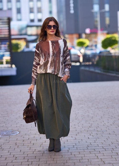 Spódnica maxi w kolorze khaki z elastyczną talią i kieszeniami, o luźnym kroju, zestawiona z wzorzystą bluzką i botkami na słupku w miejskiej stylizacji.