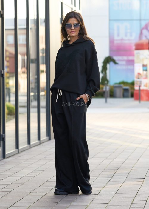 Czarny komplet dresowy damski z oversize’ową bluzą z literą M i szerokimi spodniami z elastycznym pasem, stylizacja w minimalistycznym, miejskim klimacie.
