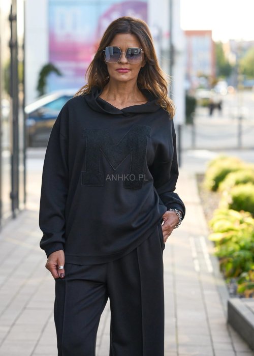 Czarny komplet dresowy damski z oversize’ową bluzą z literą M i szerokimi spodniami z elastycznym pasem, stylizacja w minimalistycznym, miejskim klimacie.