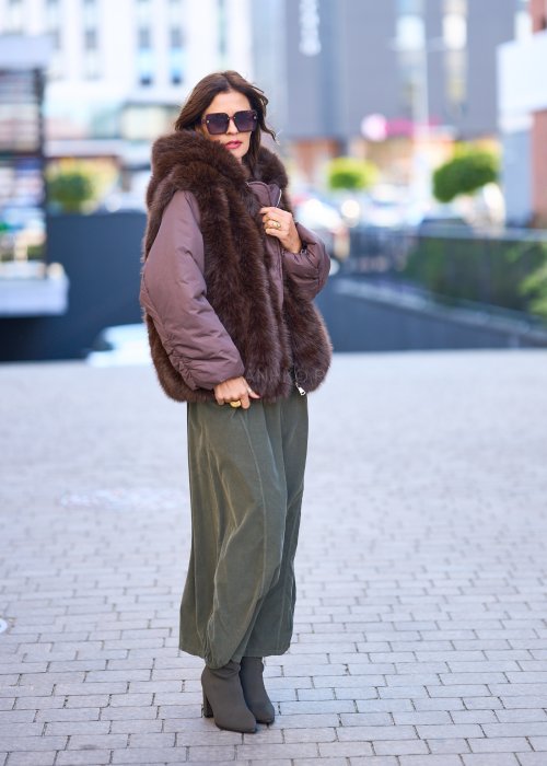 Spódnica maxi w kolorze khaki z elastyczną talią i kieszeniami, o luźnym kroju, zestawiona z wzorzystą bluzką i botkami na słupku w miejskiej stylizacji.