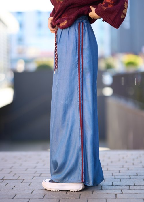 Niebieskie spodnie z lekkiego denimu o szerokich nogawkach, elastycznym pasie i ozdobnych lampasach w kolorze bordo