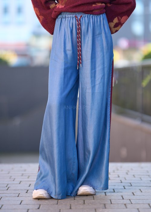 Niebieskie spodnie z lekkiego denimu o szerokich nogawkach, elastycznym pasie i ozdobnych lampasach w kolorze bordo