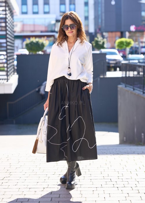 Biała bluzka koszulowa damska z dekoltem V i długim rękawem, o luźnym kroju. Stylizacja z czarną spódnicą w eleganckim, miejskim wydaniu.
