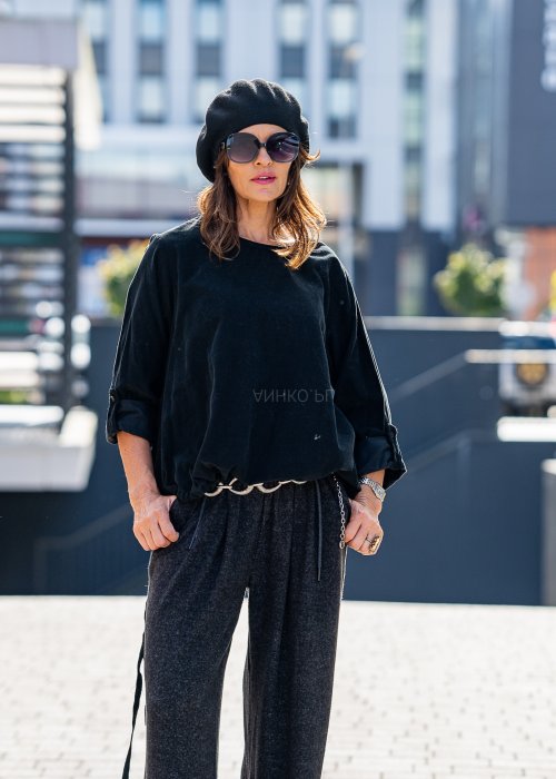Czarna bluzka oversize z długim rękawem i regulowanym dołem, stylizowana z szerokimi spodniami i beretem w miejskim, minimalistycznym looku.