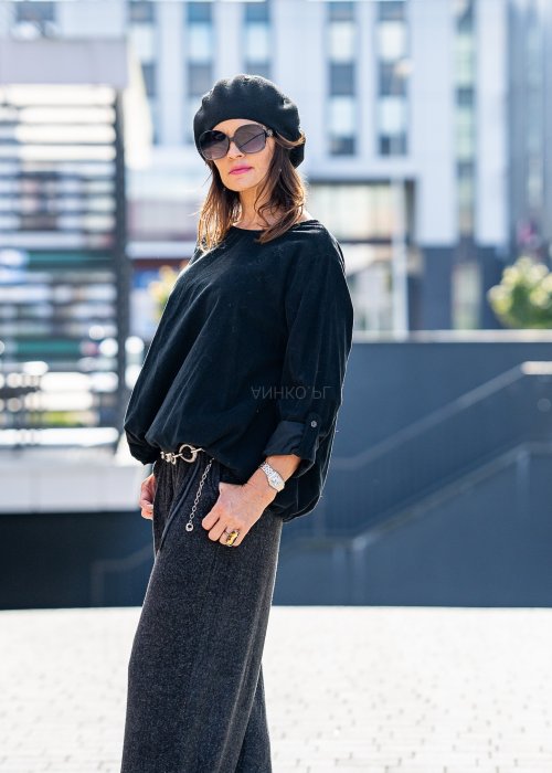 Czarna bluzka oversize z długim rękawem i regulowanym dołem, stylizowana z szerokimi spodniami i beretem w miejskim, minimalistycznym looku.