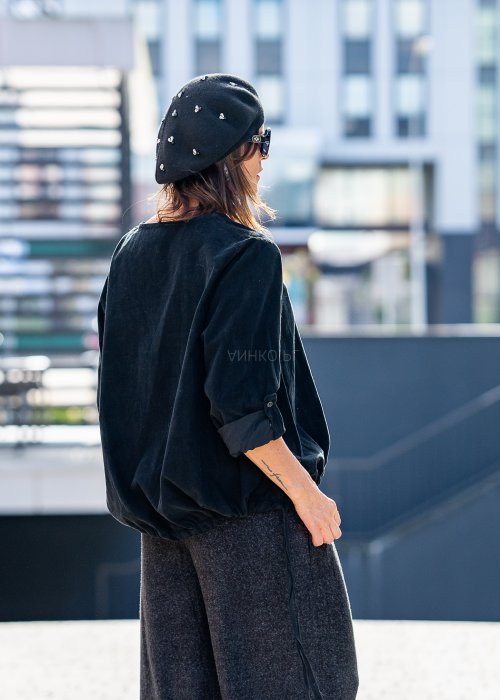 Czarna bluzka oversize z długim rękawem i regulowanym dołem, stylizowana z szerokimi spodniami i beretem w miejskim, minimalistycznym looku.