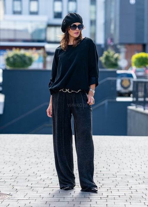 Czarna bluzka oversize z długim rękawem i regulowanym dołem, stylizowana z szerokimi spodniami i beretem w miejskim, minimalistycznym looku.