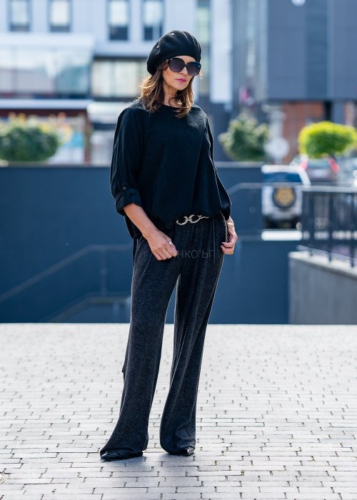 Czarna bluzka oversize z długim rękawem i regulowanym dołem, stylizowana z szerokimi spodniami i beretem w miejskim, minimalistycznym looku.