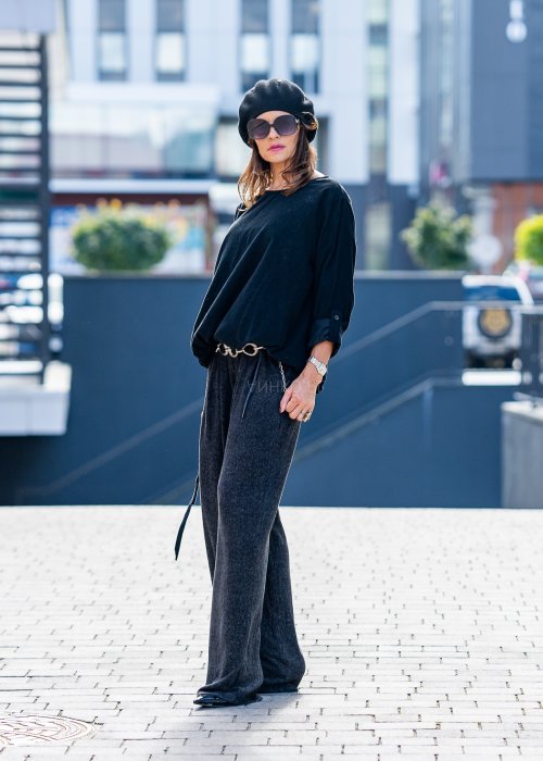 Czarna bluzka oversize z długim rękawem i regulowanym dołem, stylizowana z szerokimi spodniami i beretem w miejskim, minimalistycznym looku.