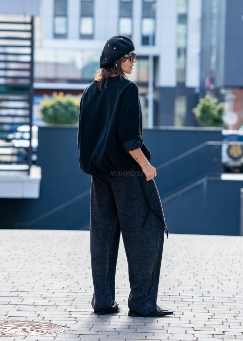 Czarna bluzka oversize z długim rękawem i regulowanym dołem, stylizowana z szerokimi spodniami i beretem w miejskim, minimalistycznym looku.