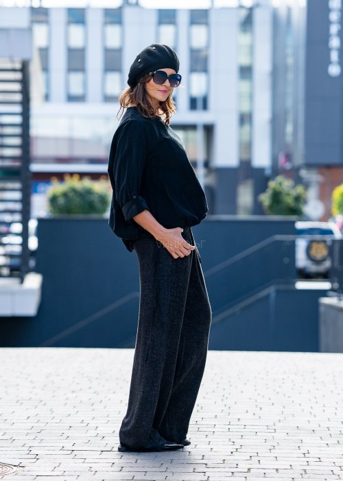 Czarna bluzka oversize z długim rękawem i regulowanym dołem, stylizowana z szerokimi spodniami i beretem w miejskim, minimalistycznym looku.