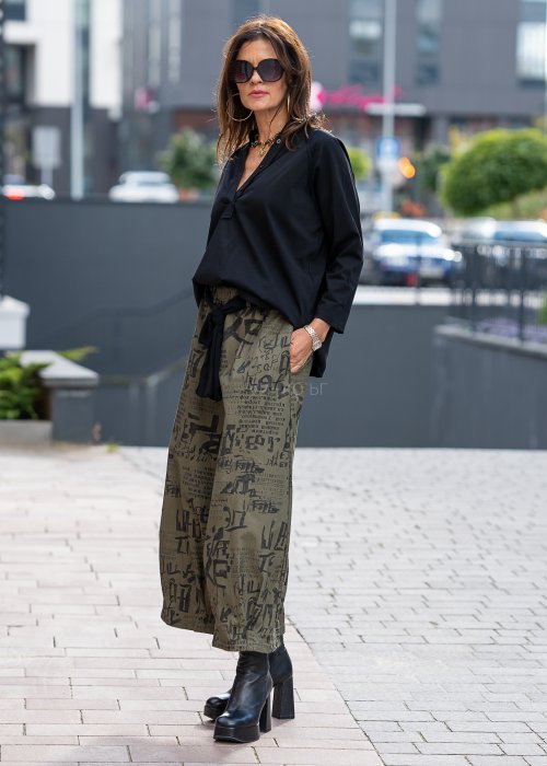 Czarna bluzka koszulowa damska z dekoltem V i długim rękawem o luźnym kroju. Stylizacja z szerokimi spodniami w miejskim, eleganckim stylu.