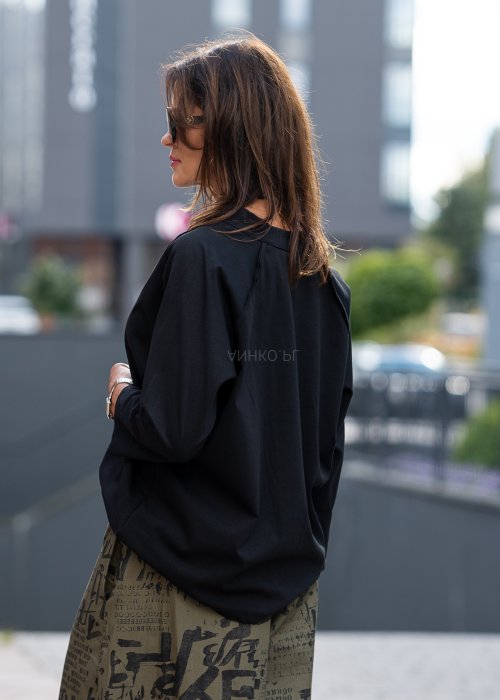 Czarna bluzka koszulowa damska z dekoltem V i długim rękawem o luźnym kroju. Stylizacja z szerokimi spodniami w miejskim, eleganckim stylu.