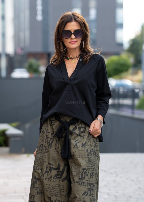 Czarna bluzka koszulowa damska z dekoltem V i długim rękawem o luźnym kroju. Stylizacja z szerokimi spodniami w miejskim, eleganckim stylu.