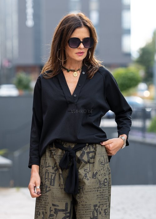 Czarna bluzka koszulowa damska z dekoltem V i długim rękawem o luźnym kroju. Stylizacja z szerokimi spodniami w miejskim, eleganckim stylu.