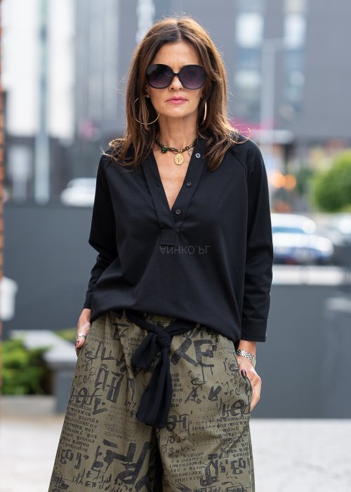 Czarna bluzka koszulowa damska z dekoltem V i długim rękawem o luźnym kroju. Stylizacja z szerokimi spodniami w miejskim, eleganckim stylu.