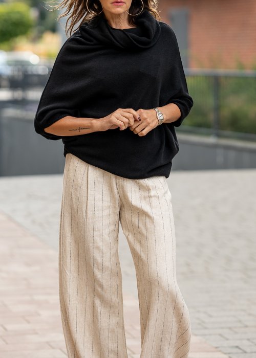 Czarny sweter oversize w stylu poncza z szerokim kołnierzem komin i luźnym krojem. Model w miejskiej stylizacji z eleganckim, minimalistycznym charakterem.