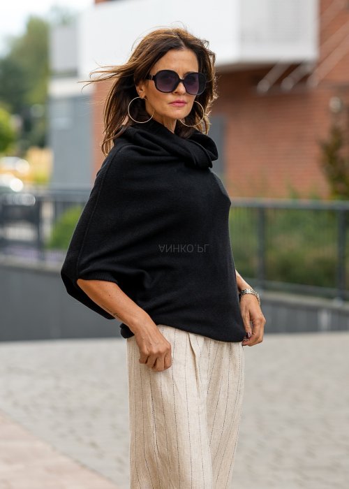 Czarny sweter oversize w stylu poncza z szerokim kołnierzem komin i luźnym krojem. Model w miejskiej stylizacji z eleganckim, minimalistycznym charakterem.