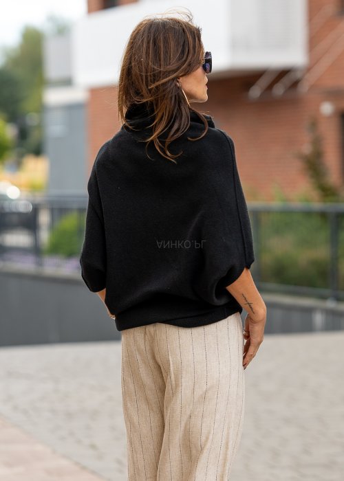 Czarny sweter oversize w stylu poncza z szerokim kołnierzem komin i luźnym krojem. Model w miejskiej stylizacji z eleganckim, minimalistycznym charakterem.