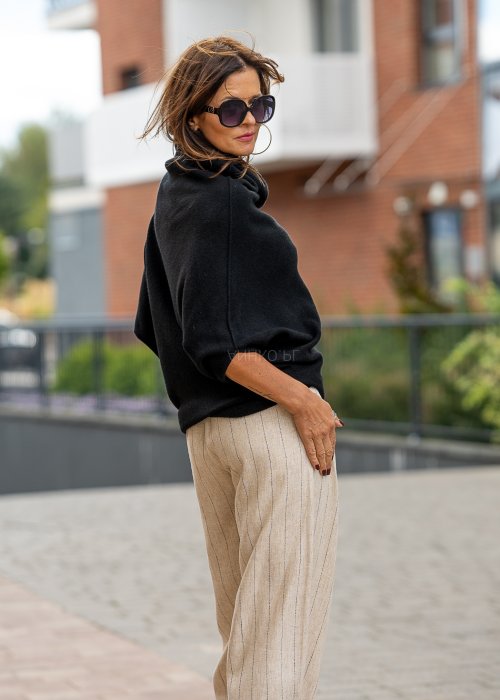 Czarny sweter oversize w stylu poncza z szerokim kołnierzem komin i luźnym krojem. Model w miejskiej stylizacji z eleganckim, minimalistycznym charakterem.