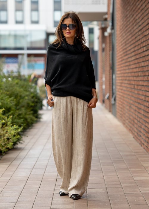 Czarny sweter oversize w stylu poncza z szerokim kołnierzem komin i luźnym krojem. Model w miejskiej stylizacji z eleganckim, minimalistycznym charakterem.