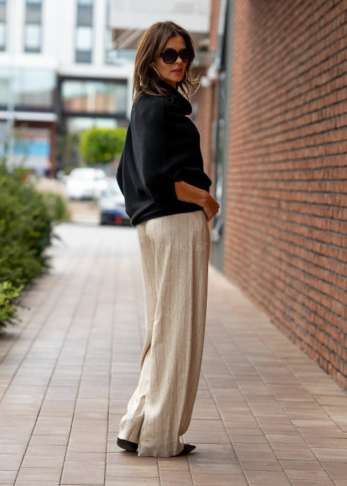 Czarny sweter oversize w stylu poncza z szerokim kołnierzem komin i luźnym krojem. Model w miejskiej stylizacji z eleganckim, minimalistycznym charakterem.