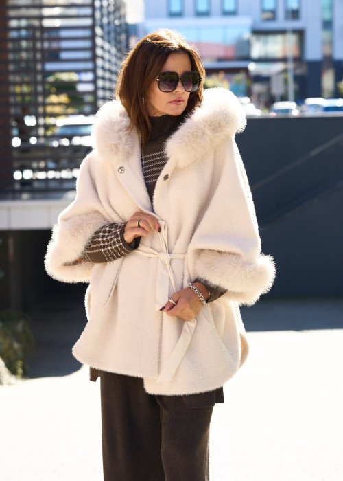 Krótka kurtka typu ponczo w kolorze ecru z kapturem i futrzanym wykończeniem rękawów