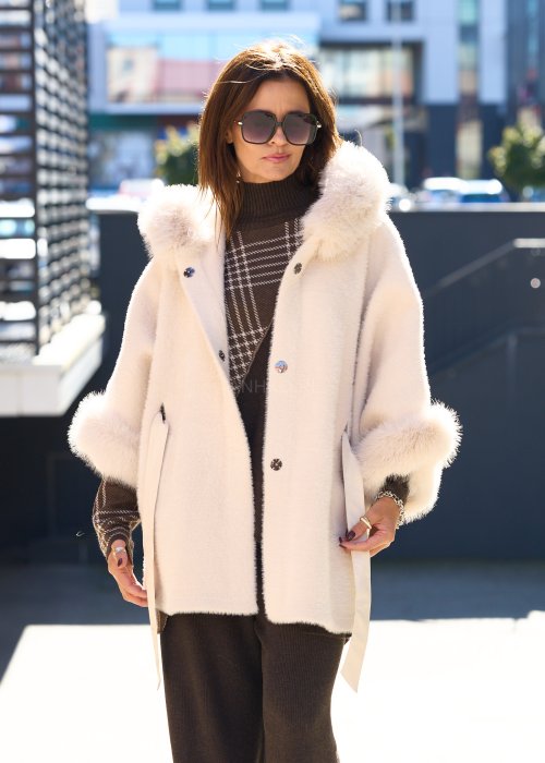 Krótka kurtka typu ponczo w kolorze ecru z kapturem i futrzanym wykończeniem rękawów