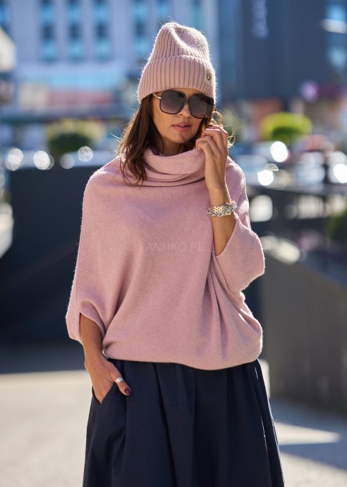 Sweter oversize w kolorze pudrowego różu z szerokim kołnierzem typu komin i luźnym krojem poncza. Model w miejskiej stylizacji, podkreślający miękką dzianinę i swobodny fason.