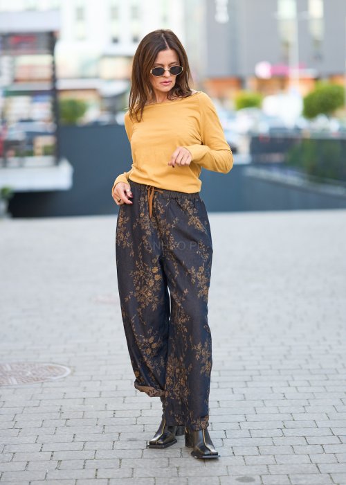 Ciemnogranatowe spodnie z szerokimi nogawkami, zdobione złotym roślinnym wzorem, zakończone gumką przy kostkach.