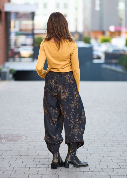 Ciemnogranatowe spodnie z szerokimi nogawkami, zdobione złotym roślinnym wzorem, zakończone gumką przy kostkach.